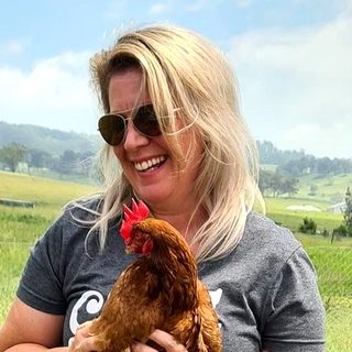 Simone, smiling, with a red hen